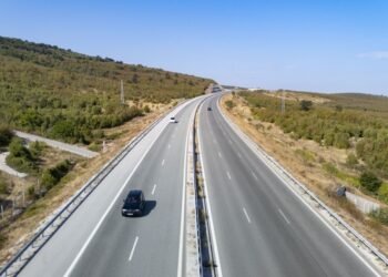 Панорамен изглед към АМ „Хемус“ с автомобили, движещи се сред зелени хълмове и открита пътна отсечка.