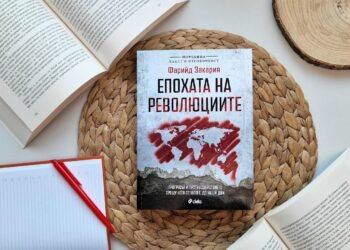 Корица на книгата „Епохата на революциите“ от Фарийд Закария, издание на „Сиела“, поставена върху плетена подложка, с отворени книги и тефтер наоколо.