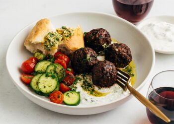 Вкусна порция сочни кюфтенца на фурна, гарнирани със свежа доматено-краставична салата, зелено орехово сосче и селски хляб, поднесени с чаша освежаваща напитка – идеалната комбинация за средиземноморска вечеря.