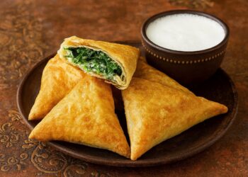 Апетитни турски банички Muska Böreği с фета и спанак, поднесени с айрян и овчарска салата върху ориенталска покривка – златисти, хрупкави и автентични.