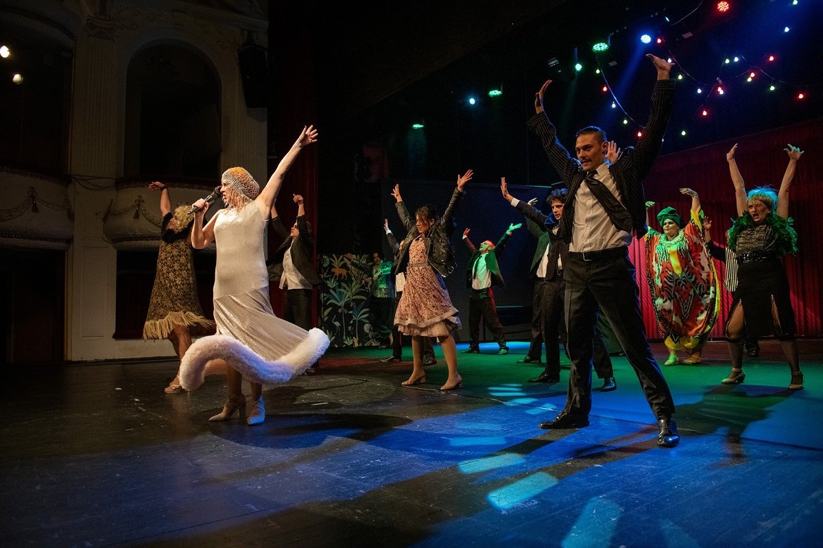 Актьори на сцената в динамична комедийна хореография по време на спектакъл на Варненския драматичен театър.