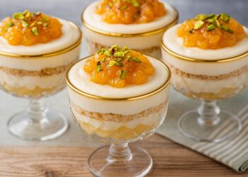 Крушов мус с бял шоколад, поднесен в стъклени чаши на зимен фон – кремообразни слоеве от круши, бисквити и бял шоколадов крем.