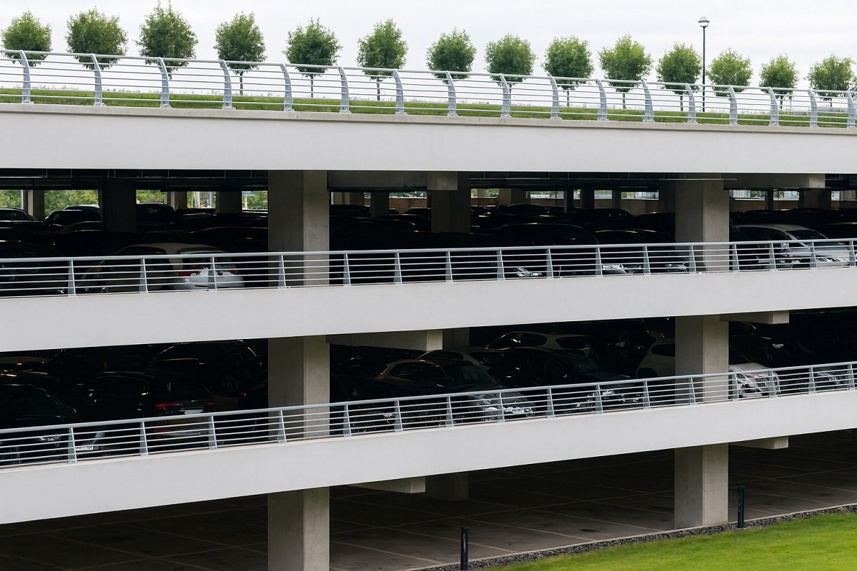 Многоетажен паркинг с няколко нива, пълен с паркирани автомобили, заснет в дъждовно време.