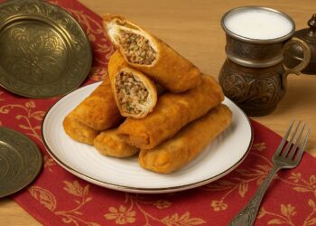 Панирани авджъ бюрек ролца, поднесени в чиния върху червена турска покривка, с меден съд с айрян и традиционни декоративни елементи на заден план.