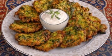 Чиния с хрупкави зеленчукови кюфтета тип мюджвер, поднесени в традиционен турски стил върху орнаментирана покривка, със сос от кисело мляко в центъра, украсен с копър.