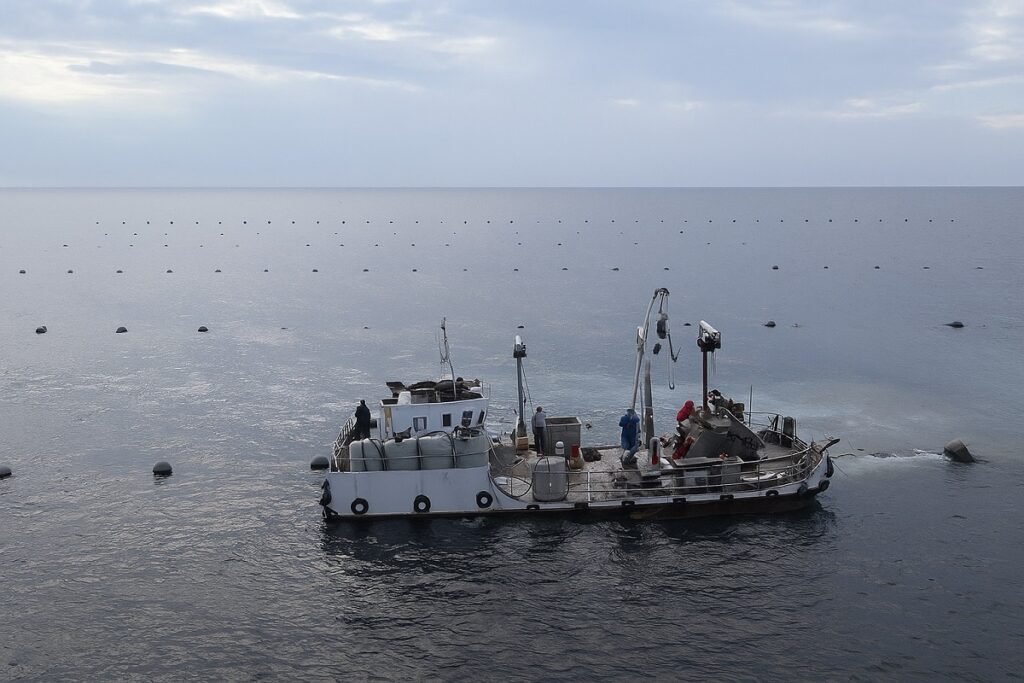 Риболовен кораб в открито море, заснет при тихо време, с разположени в далечината плаващи буйове по повърхността на водата.