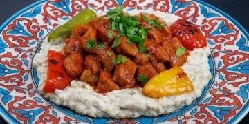 Ароматно ястие Али Назик кебап – нежни късчета агнешко в доматен сос върху крем от патладжан и кисело мляко, поднесени в чиния с турски орнаменти и печени чушки.