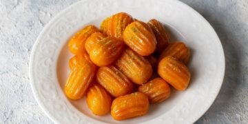 Чиния със златисти, хрупкави и сиропирани тулумбички върху светъл фон.