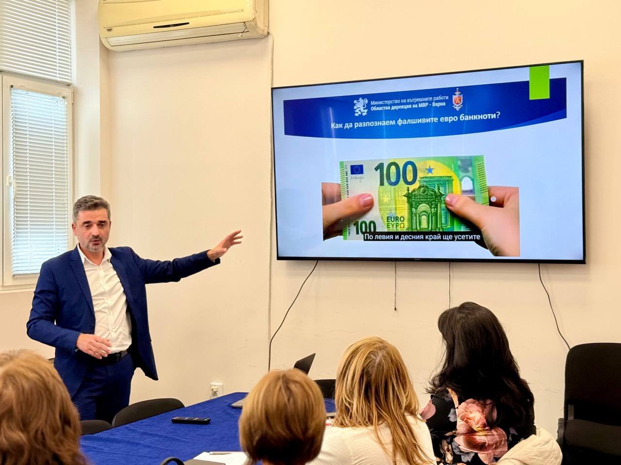 Представител на МВР изнася разяснителна презентация за разпознаване на фалшиви евро банкноти пред граждани