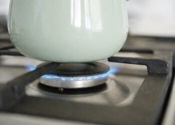 Газов котлон с включен пламък и тенджера отгоре, заснет в близък план в домашна кухня.