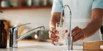 Чаша с питейна вода, пълнена от чешма в домашна кухня, символ на водоснабдяване и прекъсване на водата, реалистично изображение без надписи