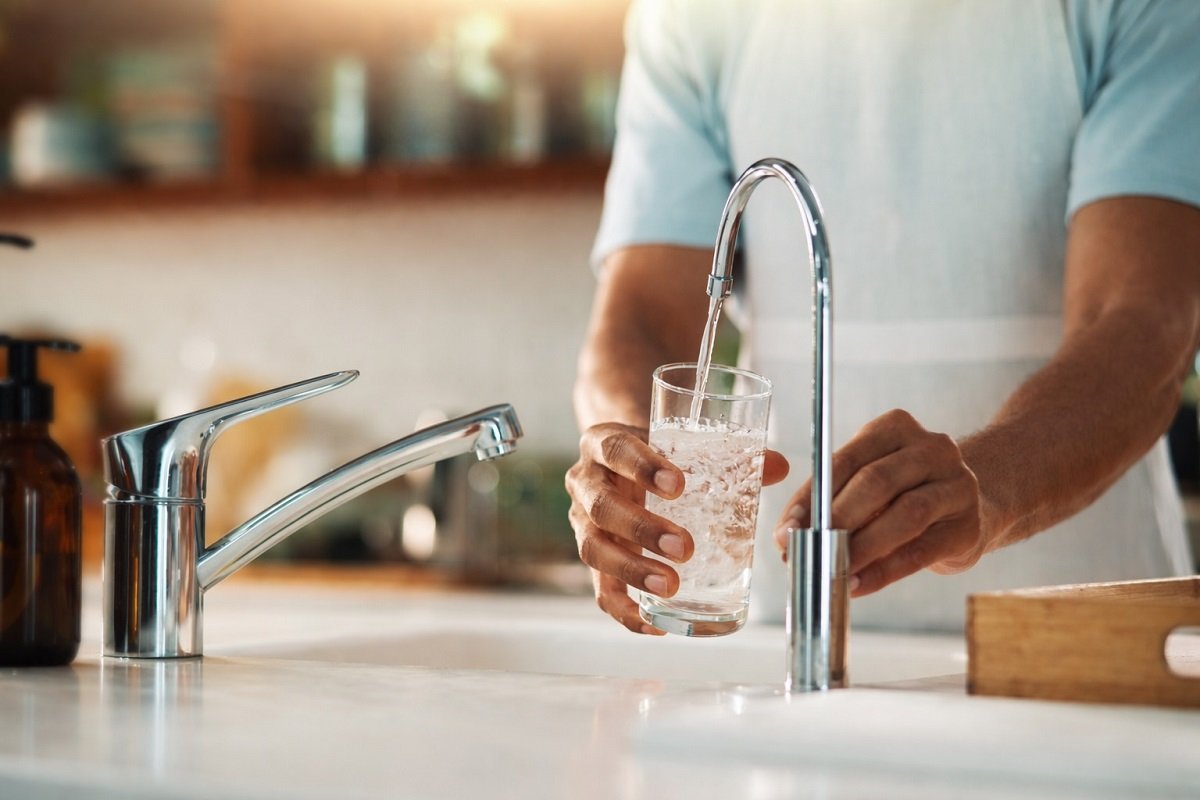 Чаша с питейна вода, пълнена от чешма в домашна кухня, символ на водоснабдяване и прекъсване на водата, реалистично изображение без надписи