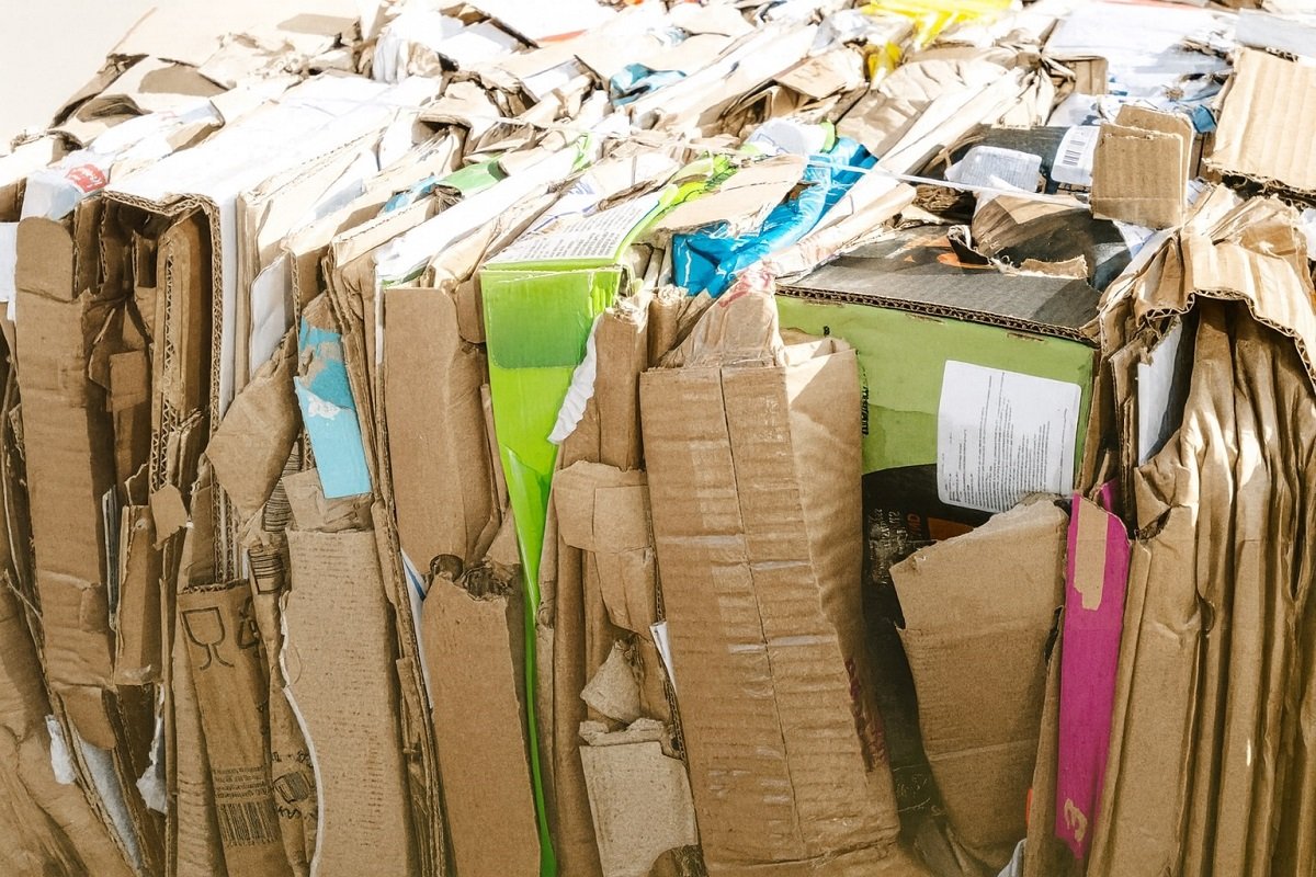 Балиран отпадъчен картон и хартия, подготвени за рециклиране, подредени на куп без надписи.