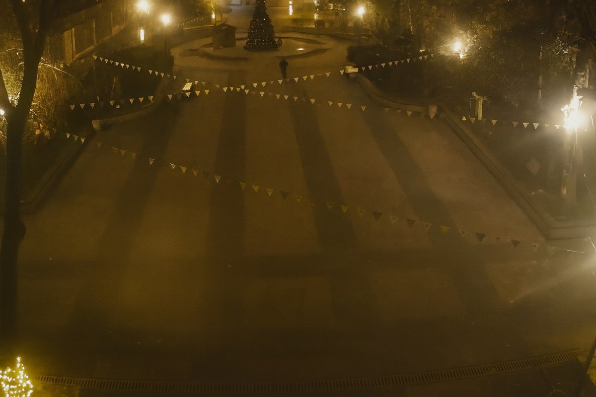 Нощен изглед към централния площад в Белослав, заснет от висока позиция, с осветена коледна елха и празнични гирлянди, озарени от улични лампи.