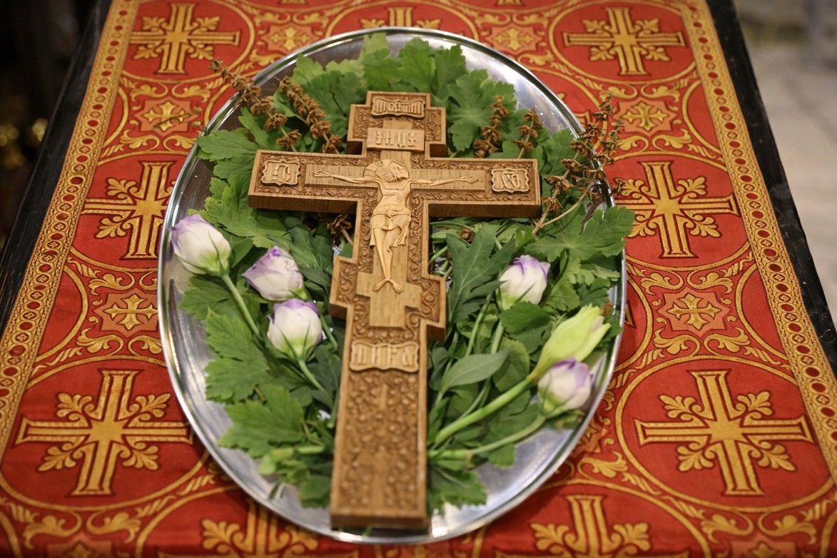 „Свещеник освещава вода с кръст и китка босилек по време на Зимен Кръстовден“