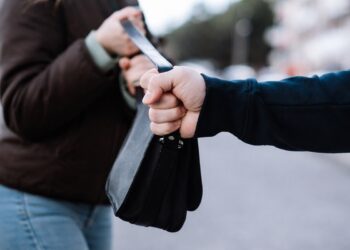 Грабеж на дамска чанта – мъж издърпва чанта от ръцете на жена на градска улица, близък план.