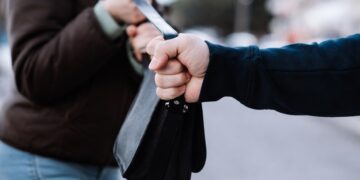 Грабеж на дамска чанта – мъж издърпва чанта от ръцете на жена на градска улица, близък план.