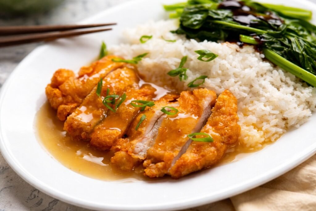 Хрупкаво панирано пилешко филе с лек сос, поднесено с бял ориз и зелени зеленчуци в азиатски стил, без надписи, хоризонтално изображение