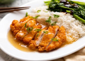 Хрупкаво панирано пилешко филе с лек сос, поднесено с бял ориз и зелени зеленчуци в азиатски стил, без надписи, хоризонтално изображение