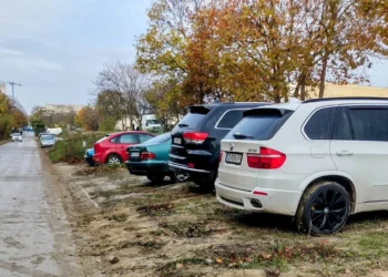 Автомобили паркирани върху кал и зелени площи във Варна до жилищни сгради