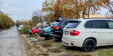 Автомобили паркирани върху кал и зелени площи във Варна до жилищни сгради